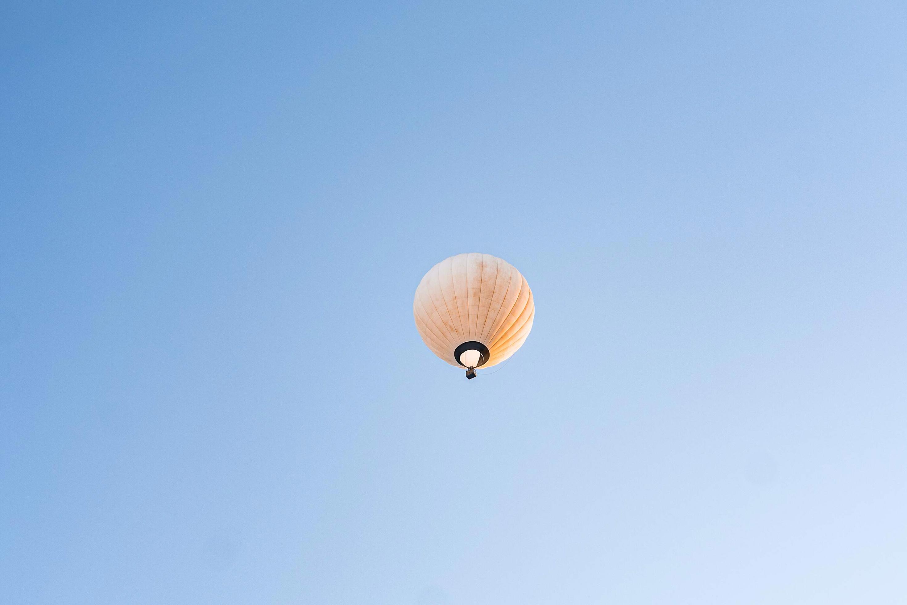 Gelber fliegender Heissluftballon steigt auf.