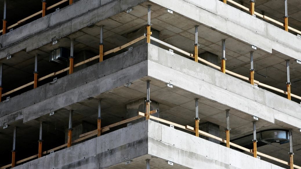 Foto: Rohbau eines Hochhauses. Zu sehen sind die Etagen aus grauem Beton, mit Holzstützen an den Rändern der Stockwerke.