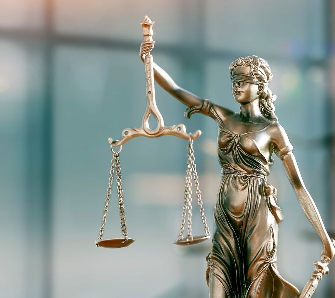 Photo: A brass statue of Justice against a blurred, light blue background.